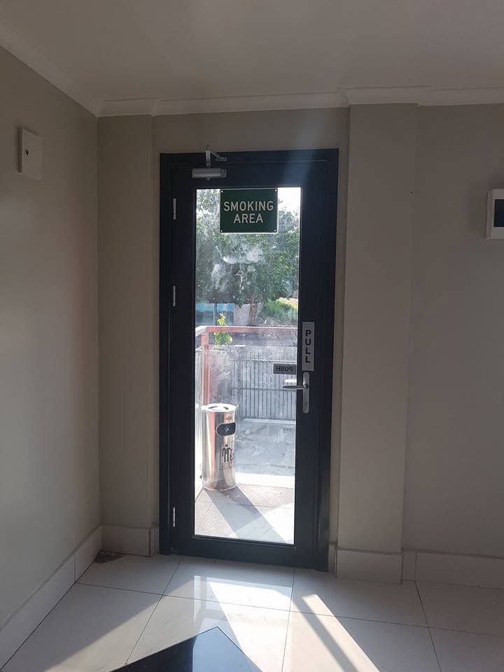 Glass door leading to a designated outdoor smoking area with a standing ashtray.