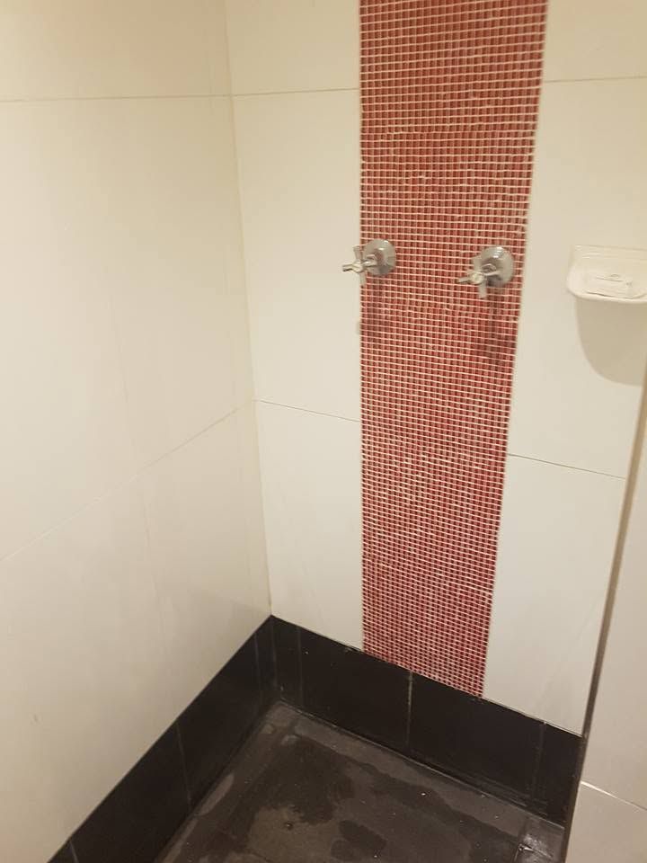 Walk-in shower area featuring a decorative red mosaic tile strip.