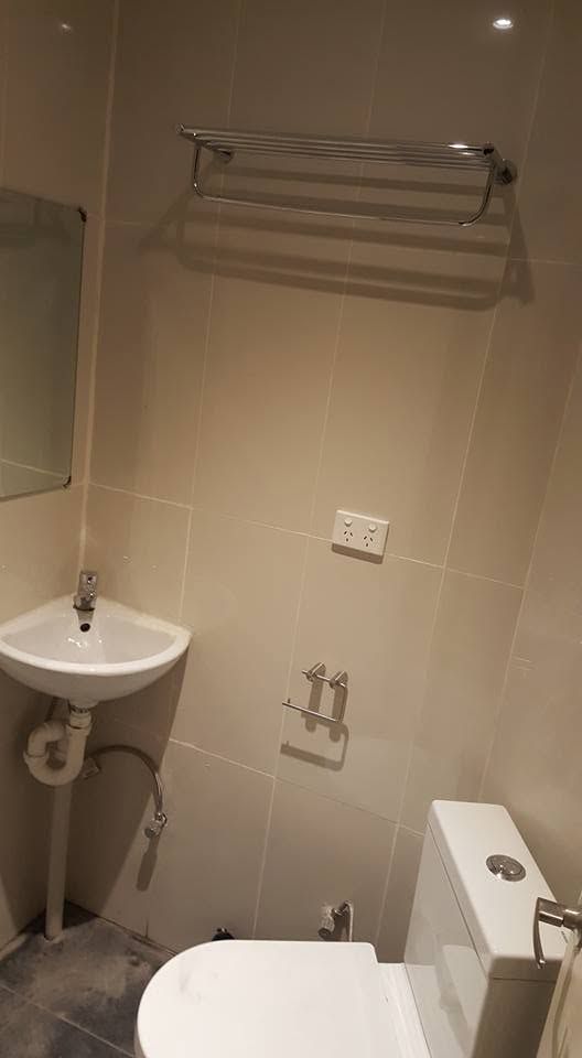 Tiled bathroom with a corner sink and wall-mounted towel rack.