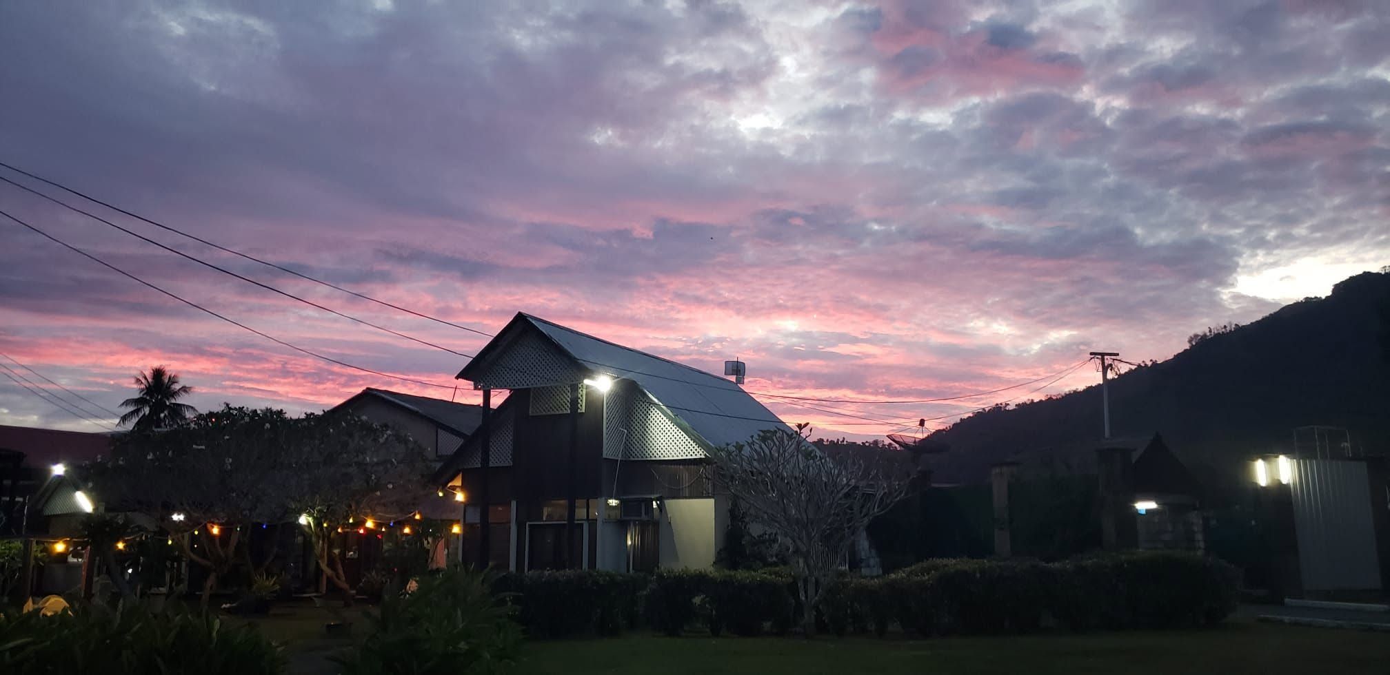 Scenic sunset view over the hotel building and surrounding hills.