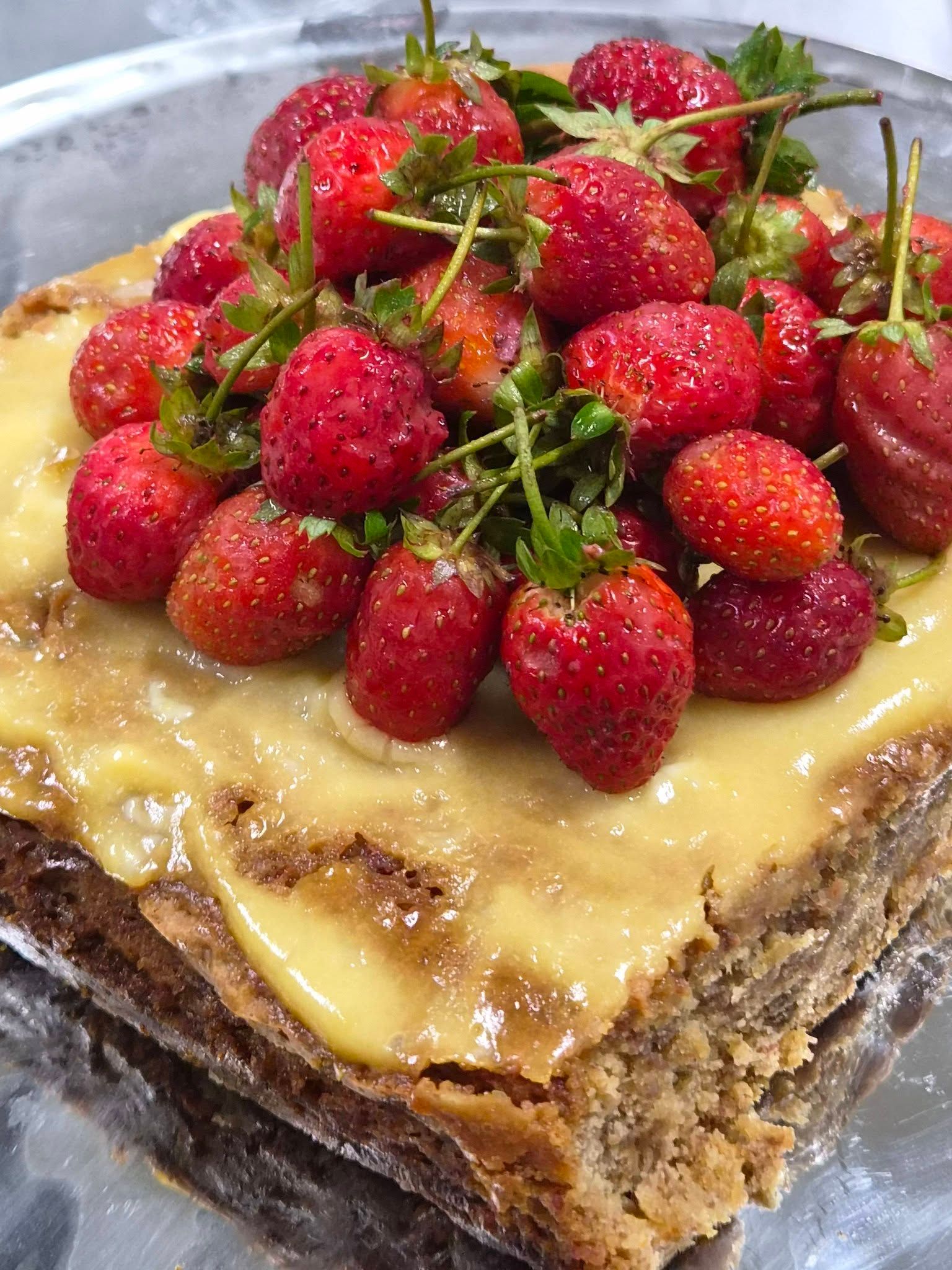 Freshly baked cake topped with a generous serving of strawberries.