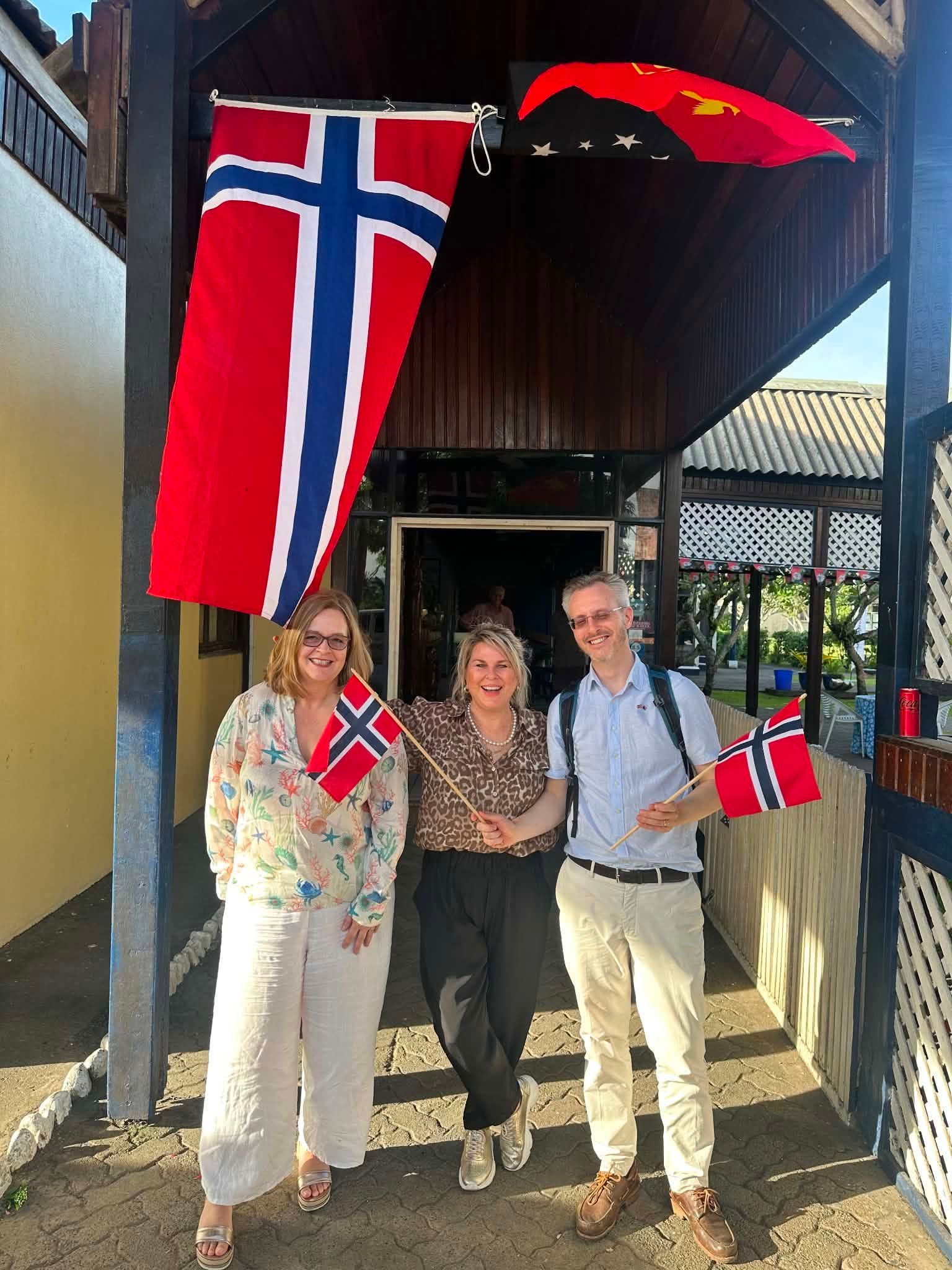 Guests posing at the hotel entrance decorated with international flags.