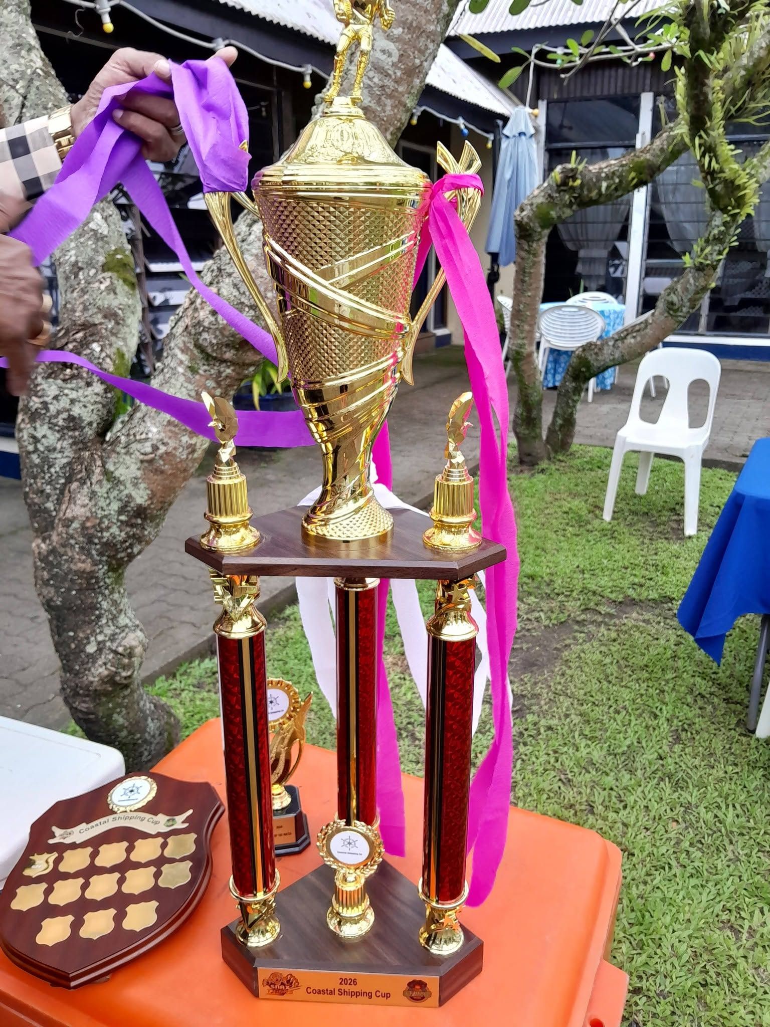Gold trophy displayed on a table during an event in the garden.