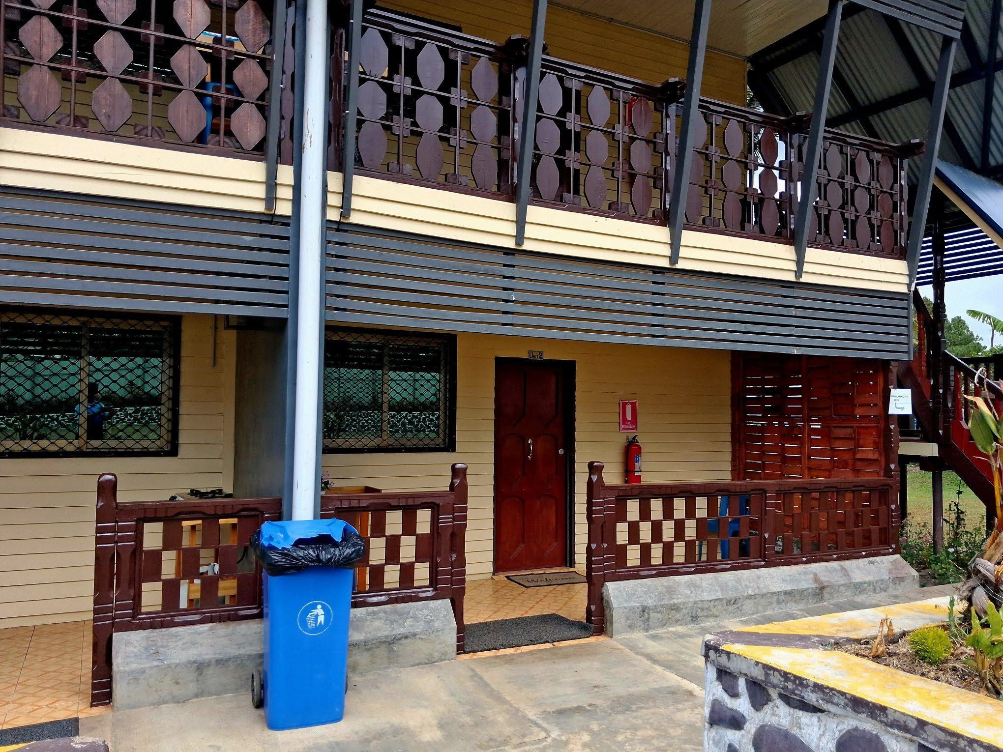 Two-story apartment complex exterior with wooden balcony railings.
