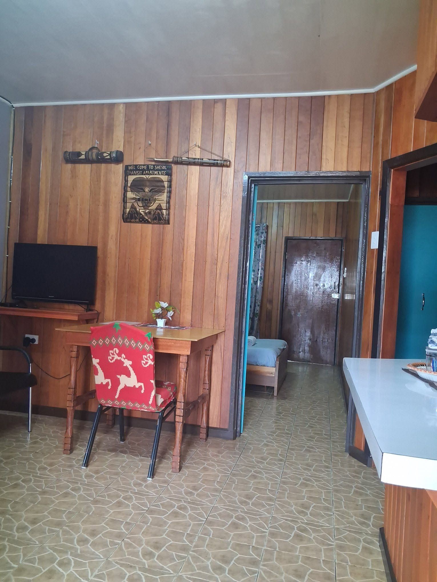 Living area featuring wood-paneled walls and a small work desk.