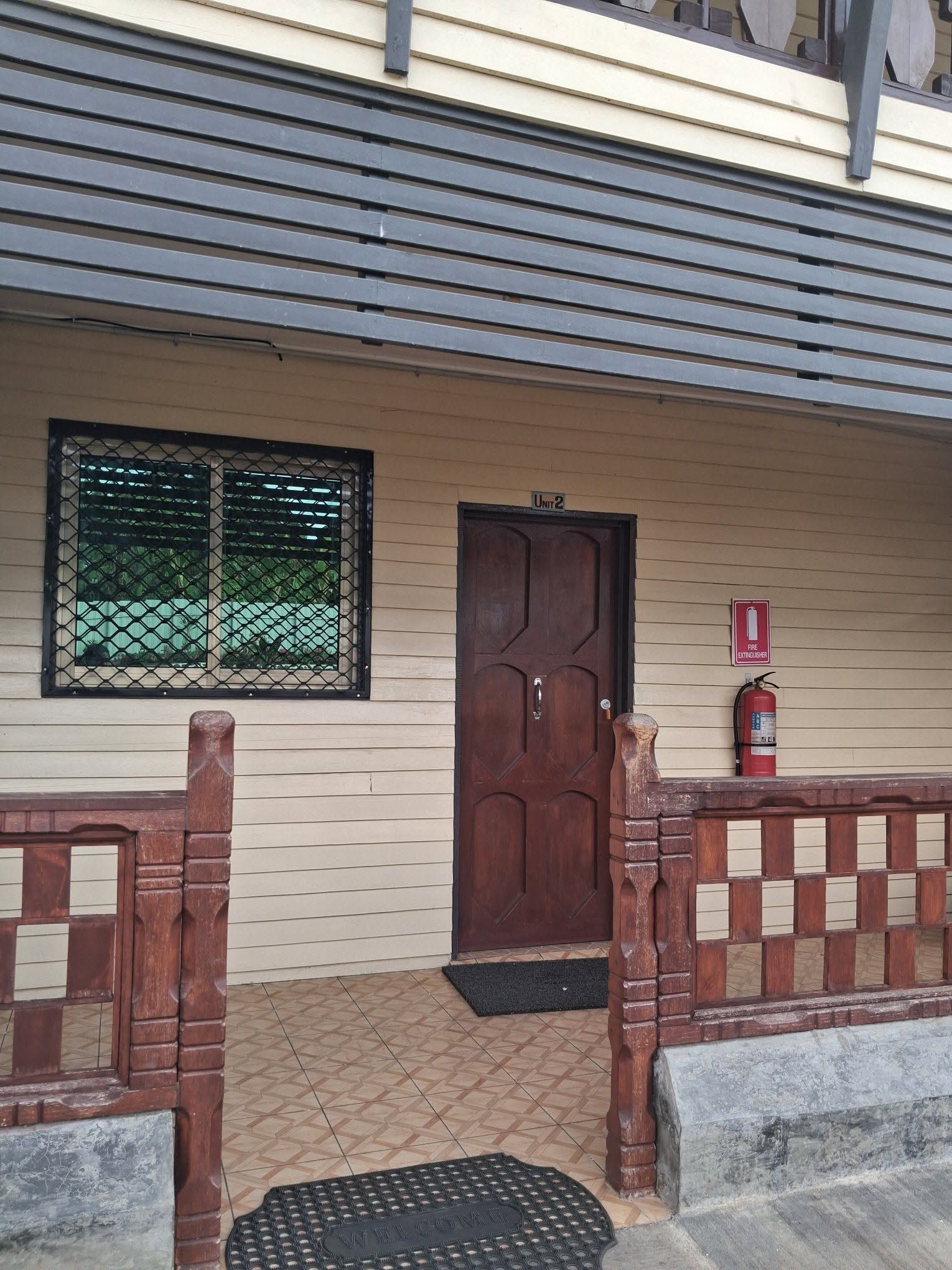 Entrance to unit two with a wooden door and red fire extinguisher.