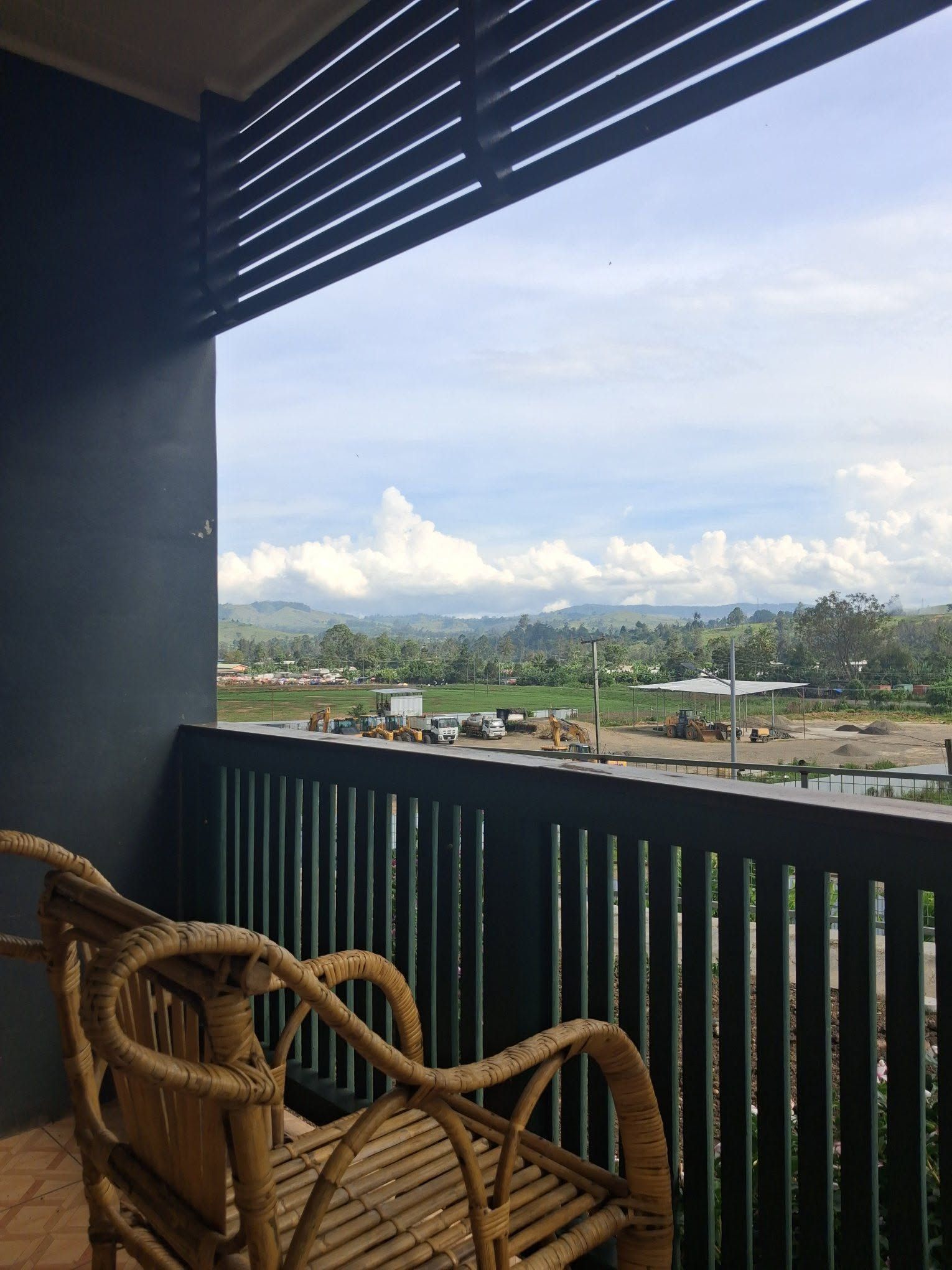 Elevated view of a transit area and green hills from the balcony.