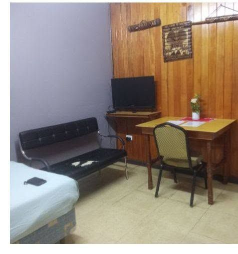 Compact workspace with a desk and chairs next to a small bed.
