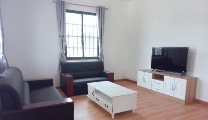 Living room area with two black leather sofas, a white coffee table, and a flat-screen TV.
