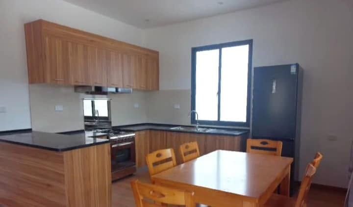 Fully equipped kitchen with wooden cabinetry, black countertops, and a dining table with chairs.