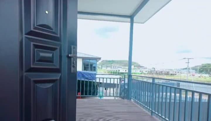 View from an open apartment door onto a balcony overlooking the surrounding estate.