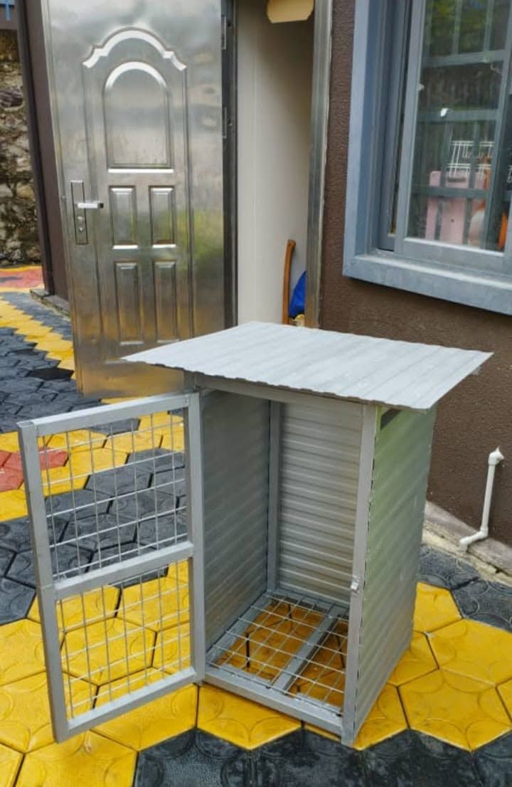A metal utility cage or gas cylinder enclosure placed on yellow and black patterned tiles.