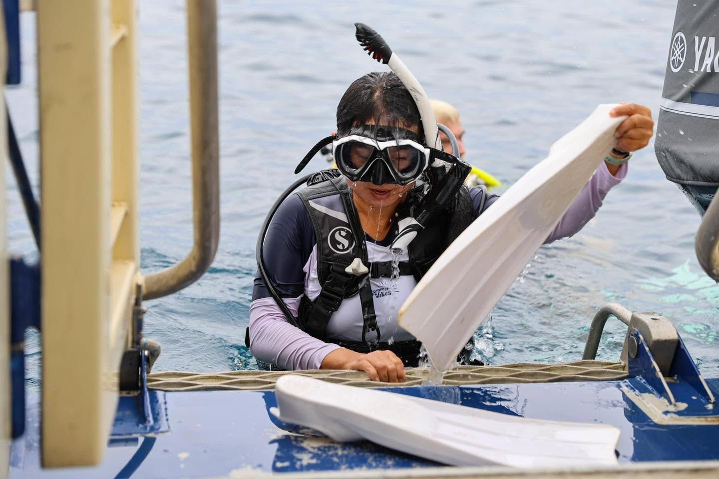 Diver wearing a mask and fins entering the water from a boat