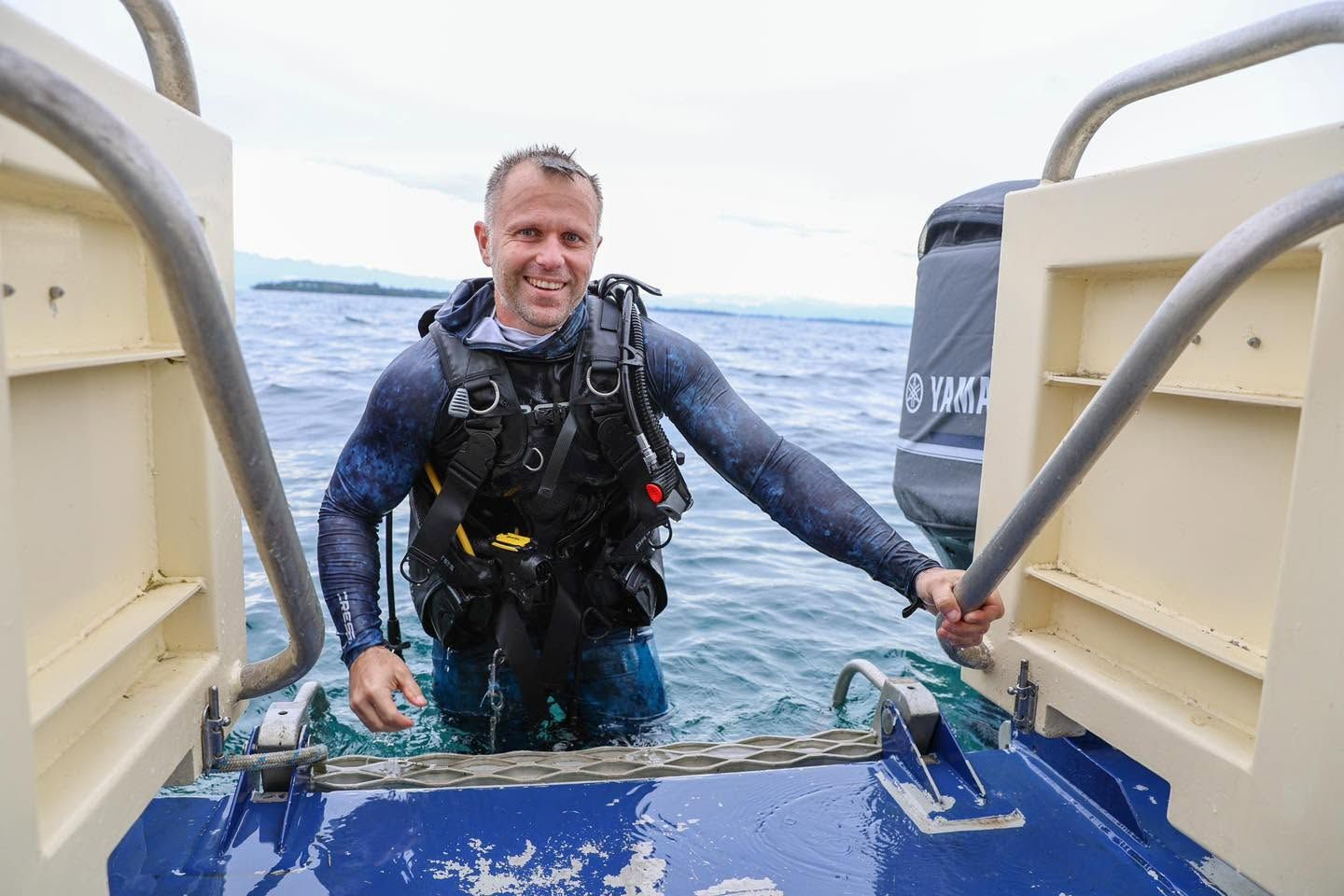 Scuba diver in full gear on the boarding ladder of a boat