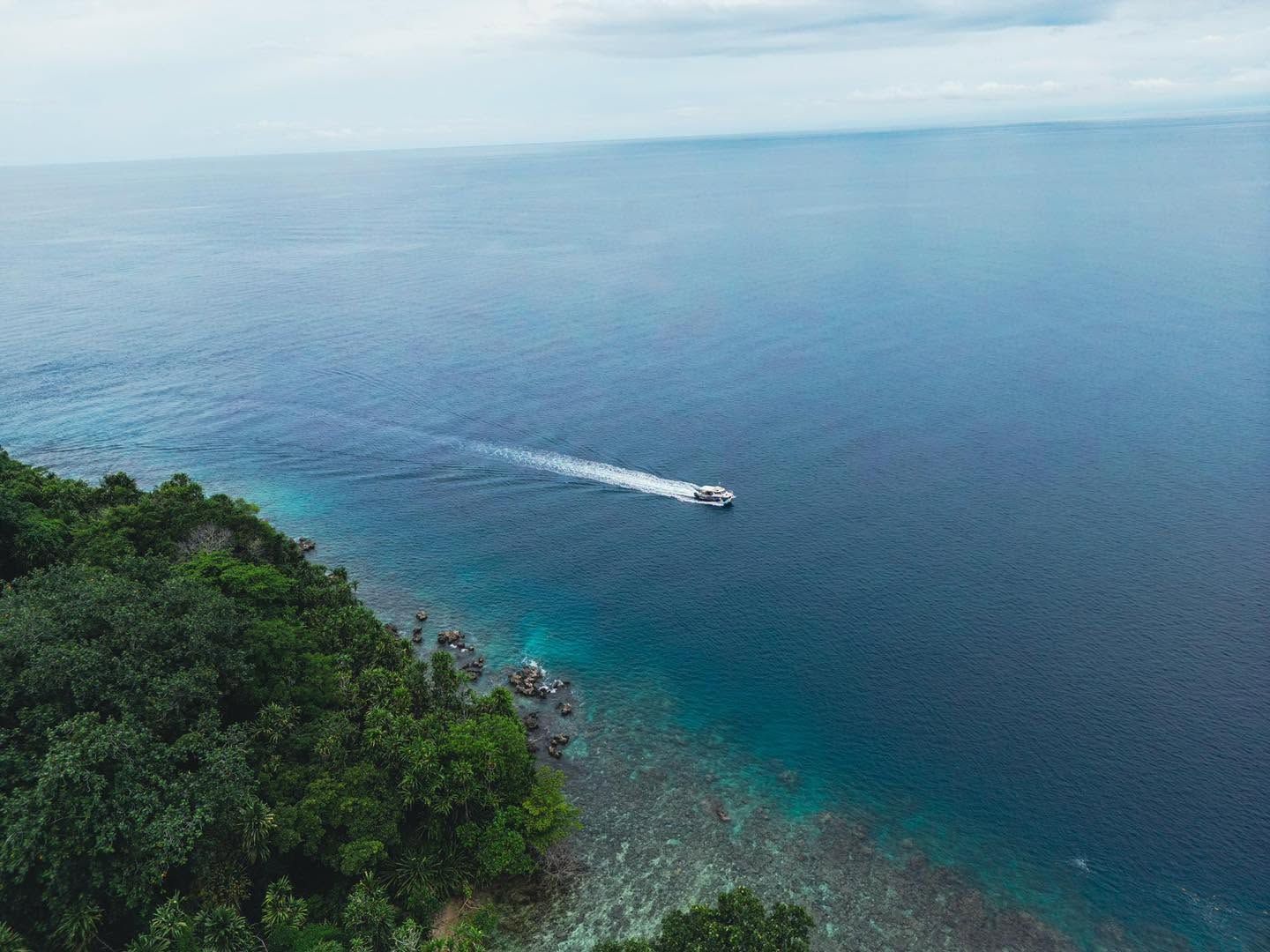 Aerial view of a motorboat cruising along the tropical coast