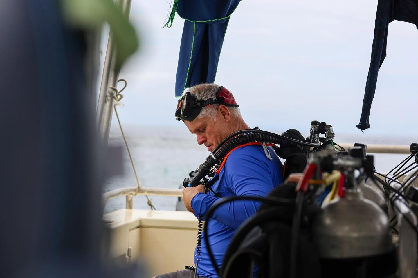Diver adjusting equipment on a boat before a dive