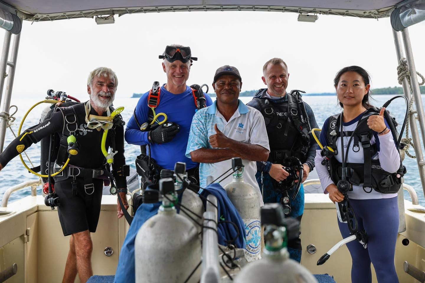 Dive instructors and guests posing on a dive boat