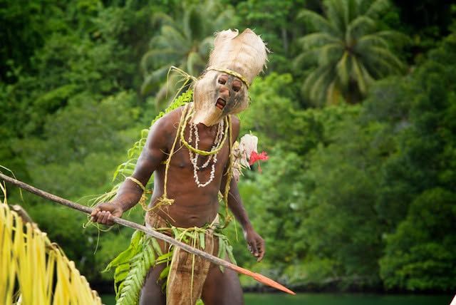Traditional cultural performer in tribal dress and mask.