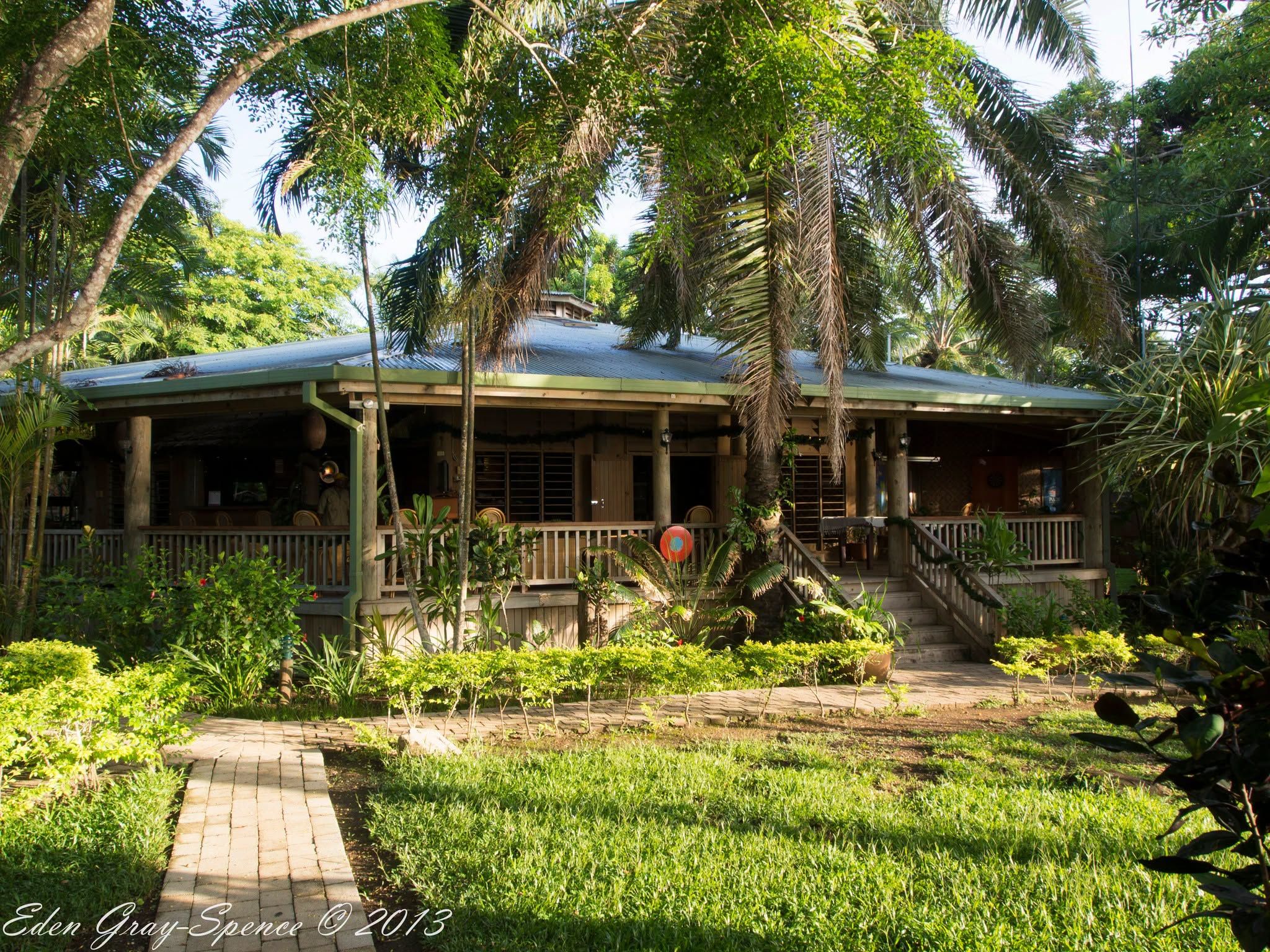 Exterior view of the wooden resort structure surrounded by palm trees.
