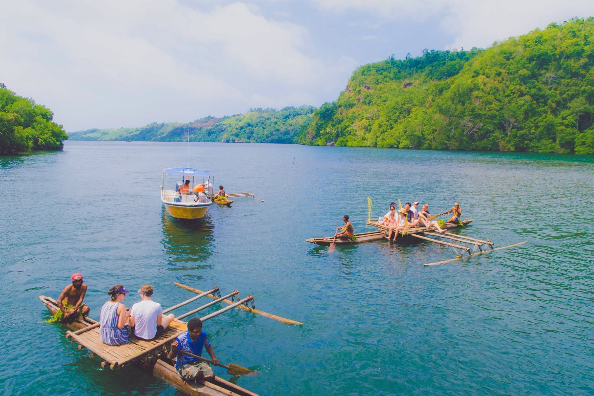 Guests on traditional bamboo rafts and a motorboat in Tufi fjords.