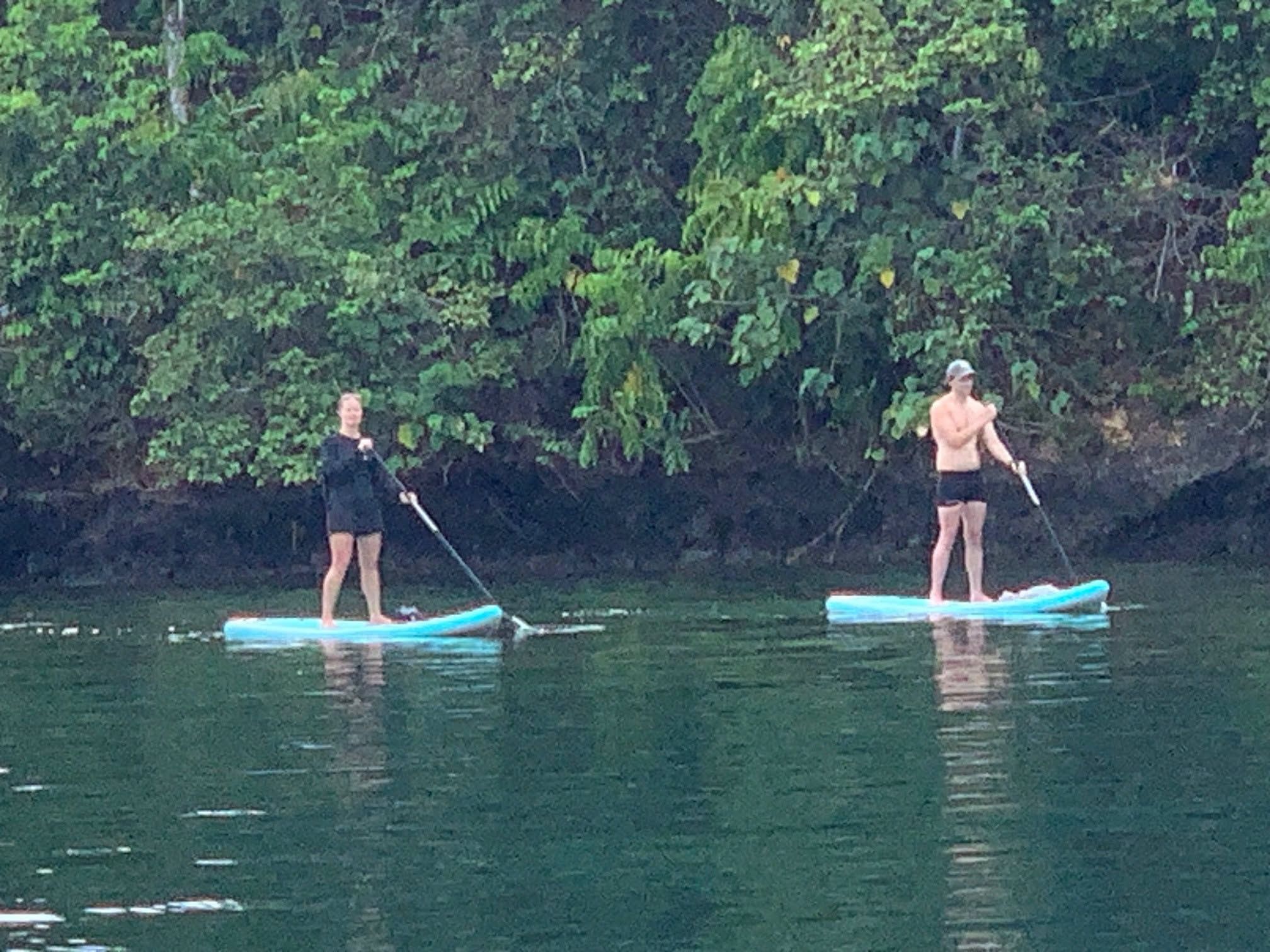 Guests paddleboarding on the calm waters of the tropical fjord.