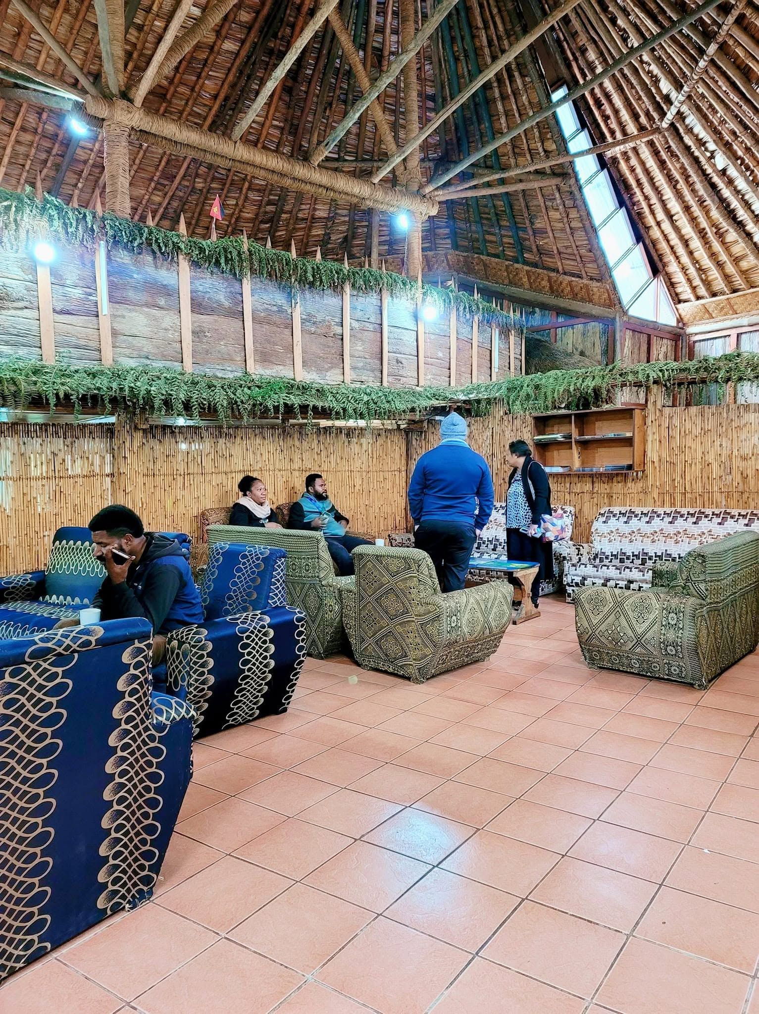 Spacious communal lounge with thatched roofing and comfortable armchair seating.